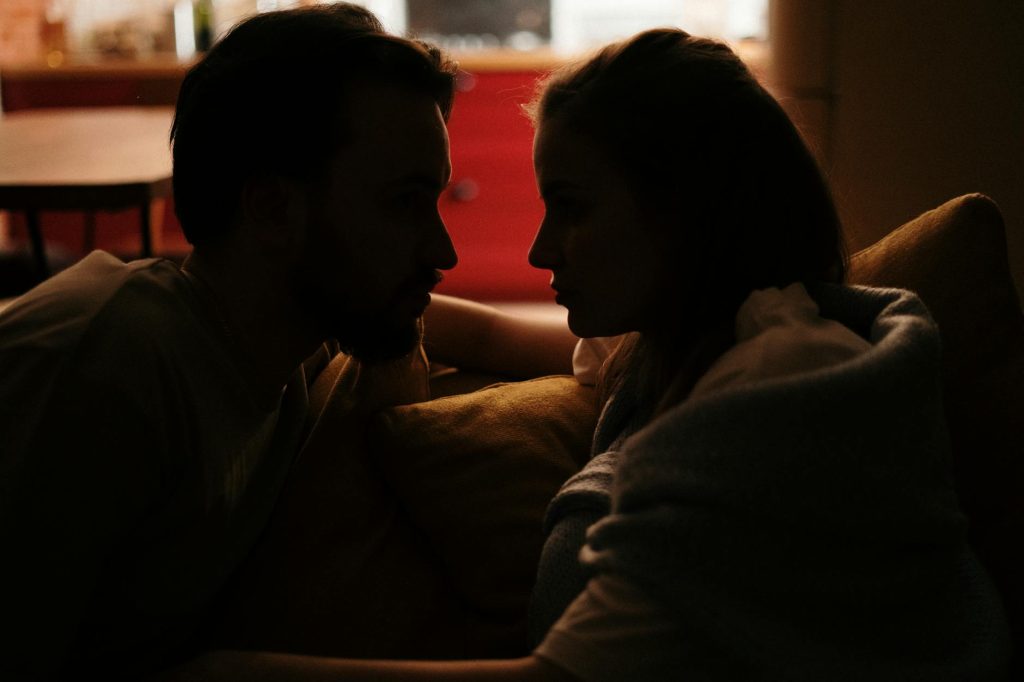 A cozy moment shared by a couple in a dimly lit home environment.