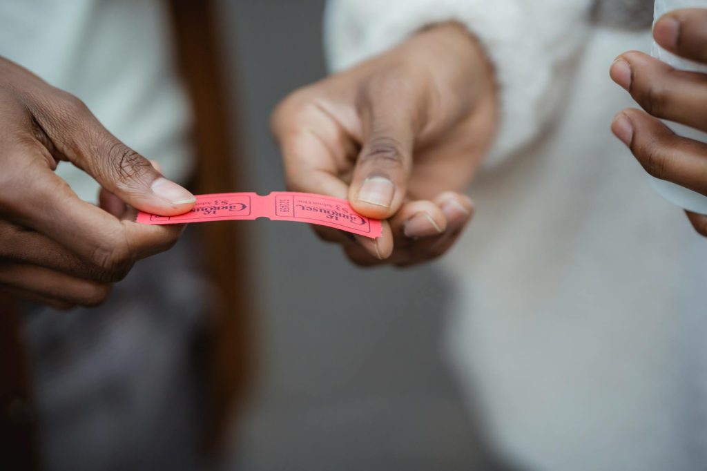 Crop unrecognizable African American friends holding small paper tickets in hands on street in daytime