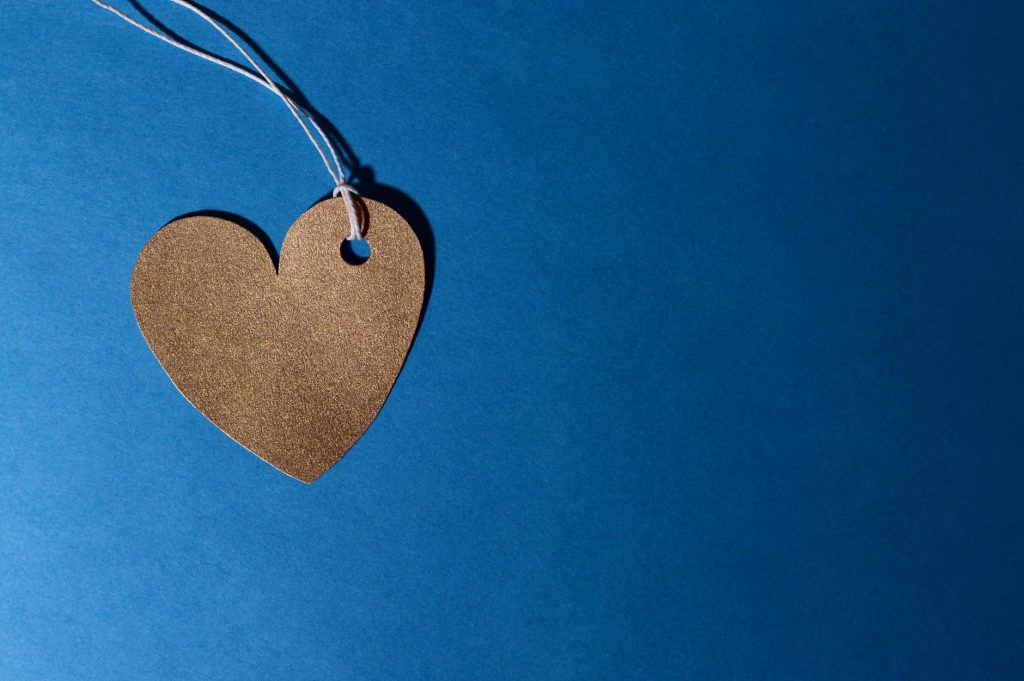 Heart-shaped cardboard cutout with string on a vivid blue background, symbolizing love.