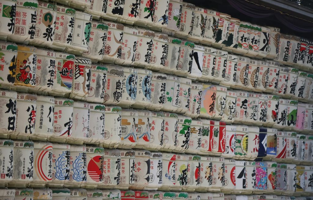 Rows of decorative sake barrels stacked at a Japanese shrine, showcasing traditional artistry and culture.