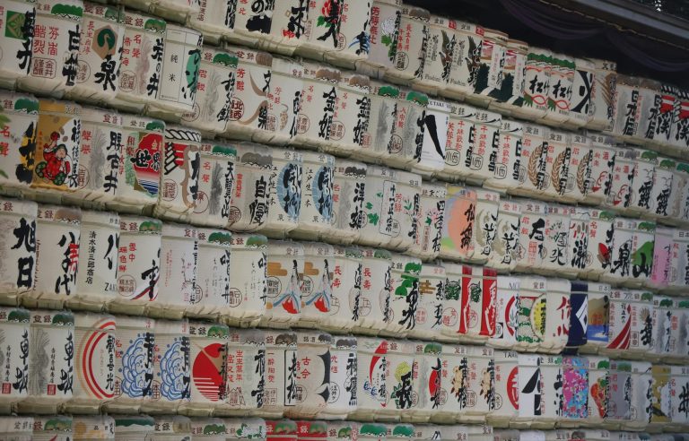 Rows of decorative sake barrels stacked at a Japanese shrine, showcasing traditional artistry and culture.