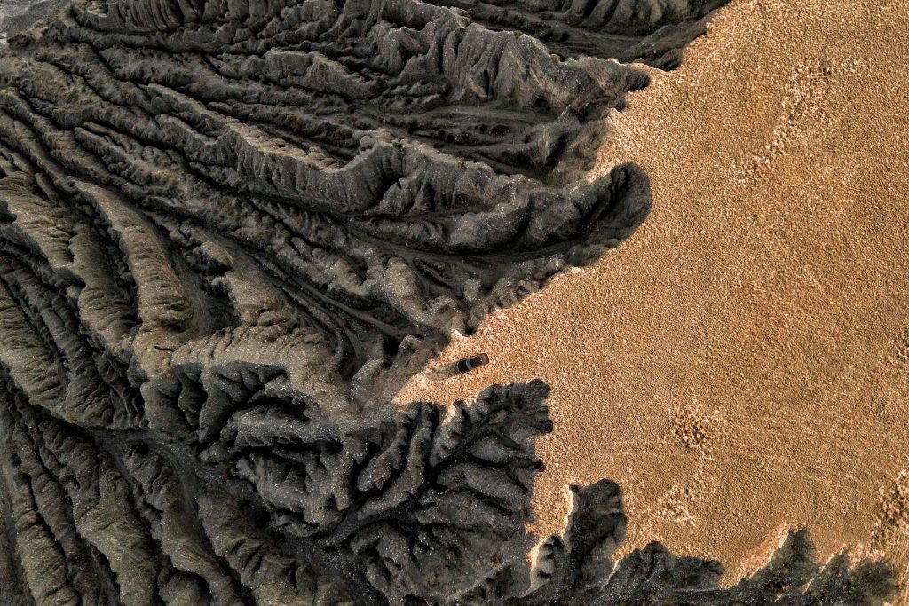 Drone capture of a barren, eroded geological formation in a desert, showcasing dramatic textures.