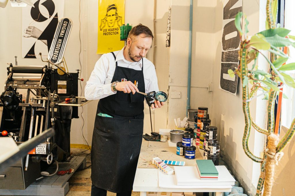 An adult male artist mixing paint in a creative workshop setting.