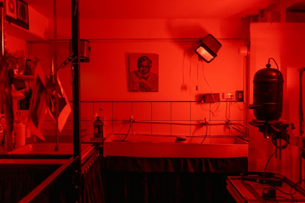A nostalgic look at a red-lit film photography darkroom, evoking vintage charm and analog processes.
