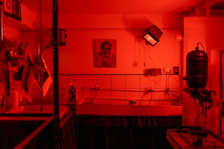 A nostalgic look at a red-lit film photography darkroom, evoking vintage charm and analog processes.