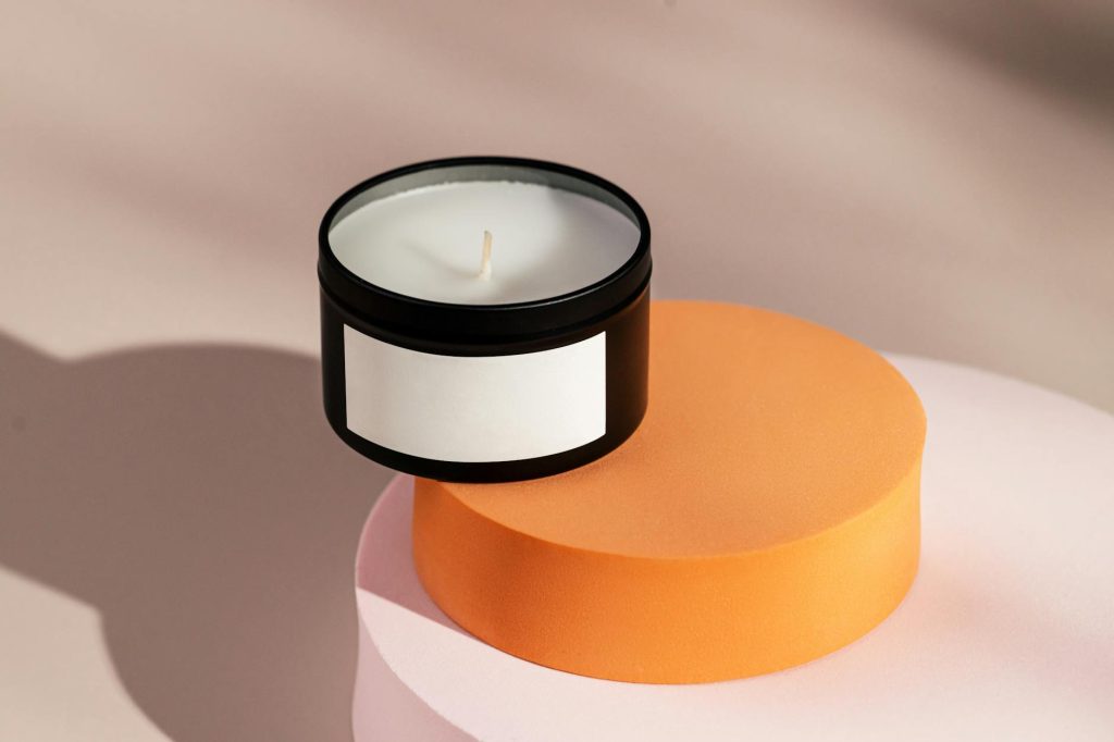 Stylish black candle on pastel geometric stands with blank label, perfect for branding concepts.