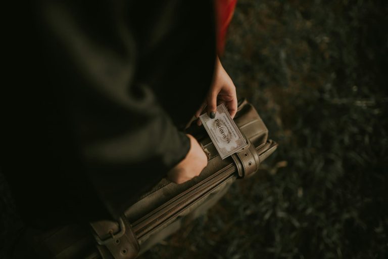 A person holding a vintage-style train ticket at an outdoor location.
