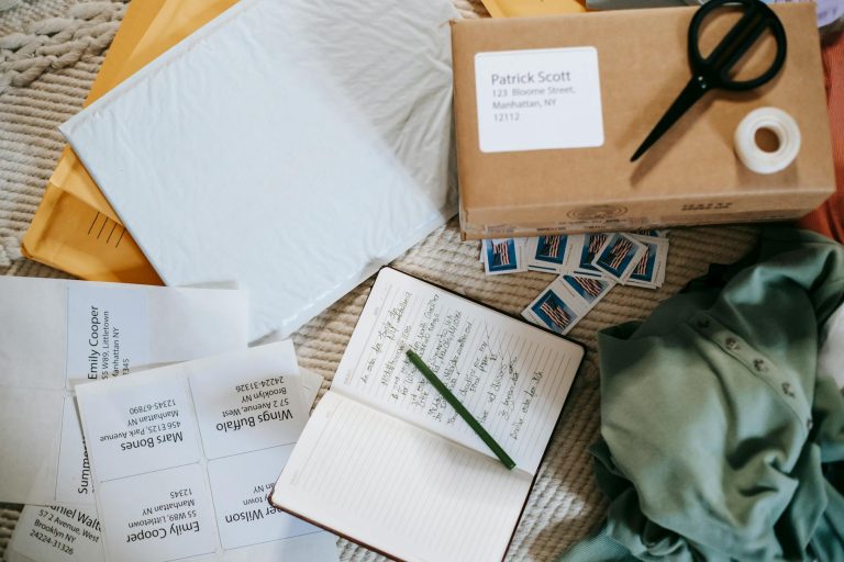 Top view of a workspace with mailing supplies, labels, and a planner for organized shipping.