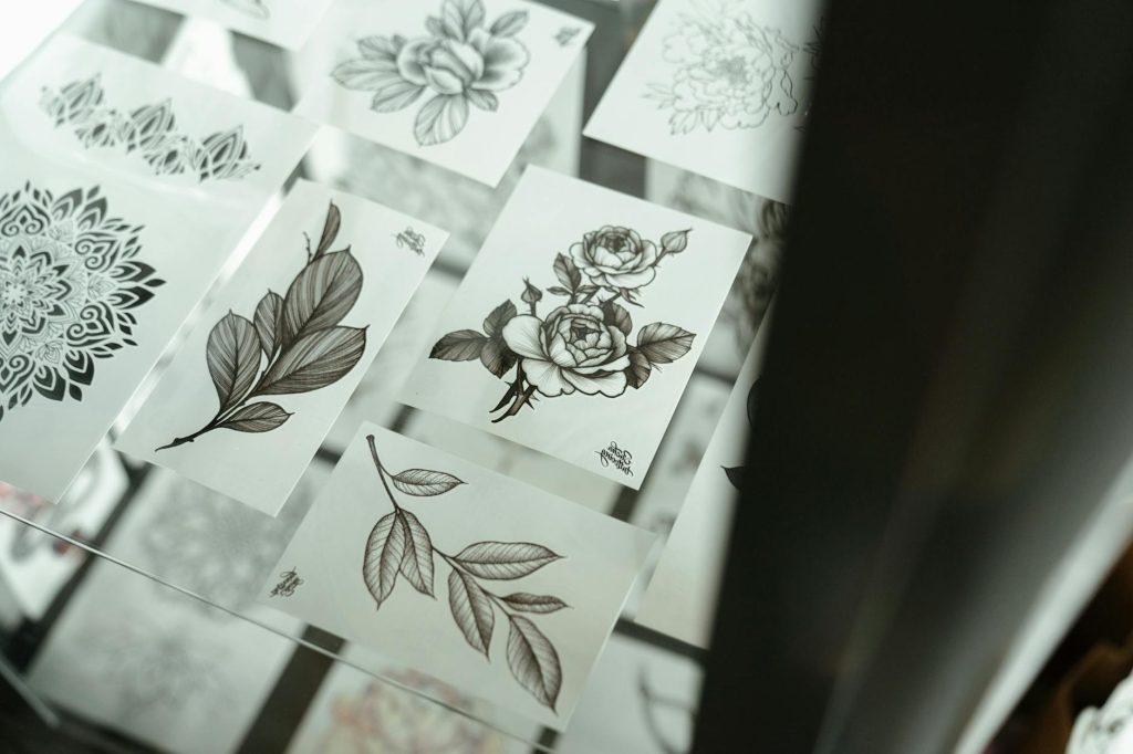 Intricate floral and abstract tattoo design sheets displayed in a tattoo studio.