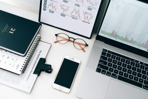Organized workspace featuring laptop, smartphone, and graphs displaying financial data.
