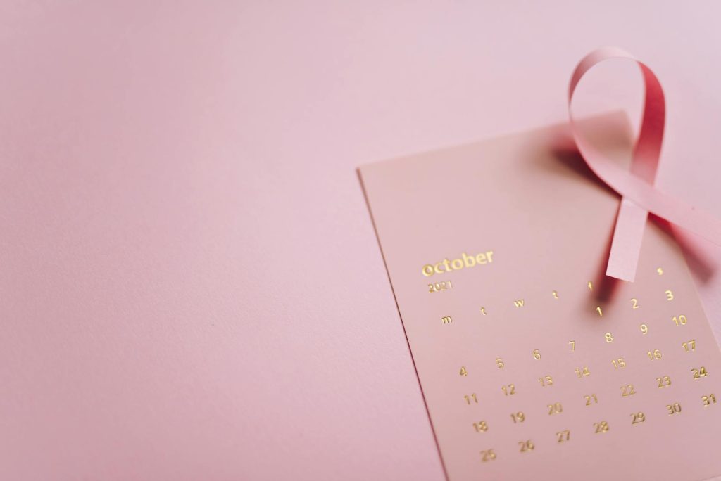 October breast cancer awareness with pink ribbon and calendar highlighting the fight against cancer.