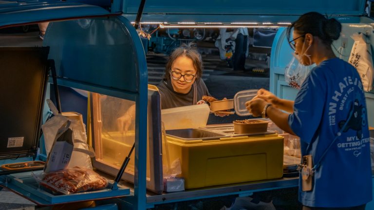Street food vendor serving customers at a vibrant night market.
