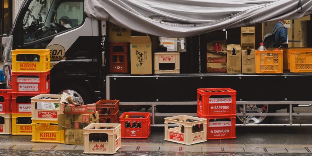 Stacked crates of Japanese beer bottles on a delivery truck in city street.
