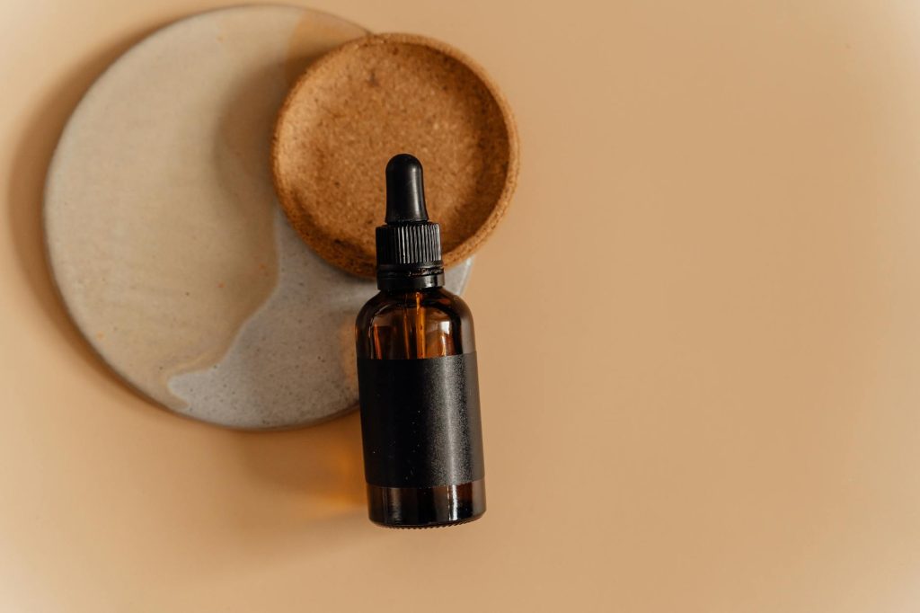 Elegant brown glass dropper bottle on artistic ceramic plates, perfect for skincare product displays.