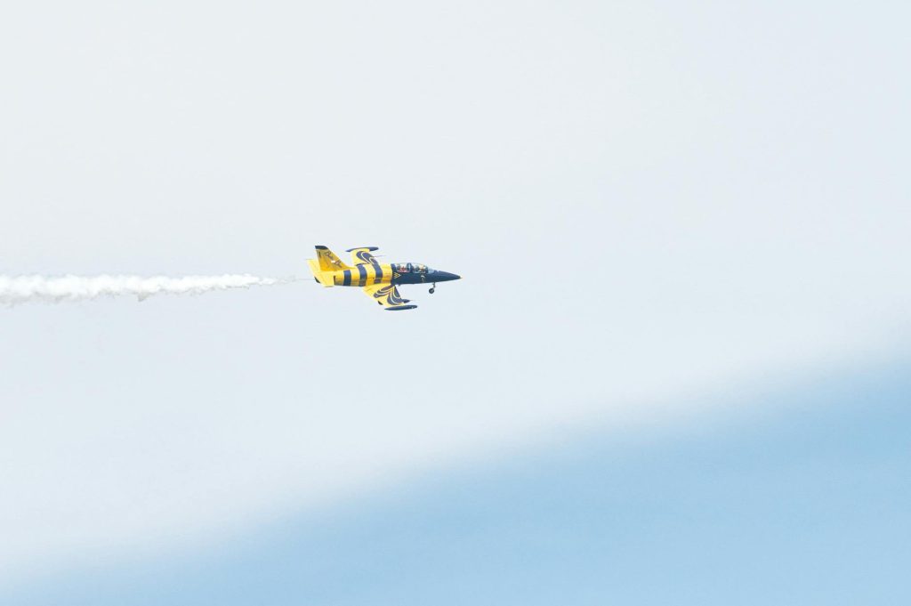 A vibrant yellow stunt plane performing aerobatics against a clear sky in Poprad, Slovakia.