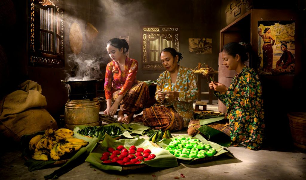 Group of women in traditional Indonesian setting preparing food with vibrant colors.