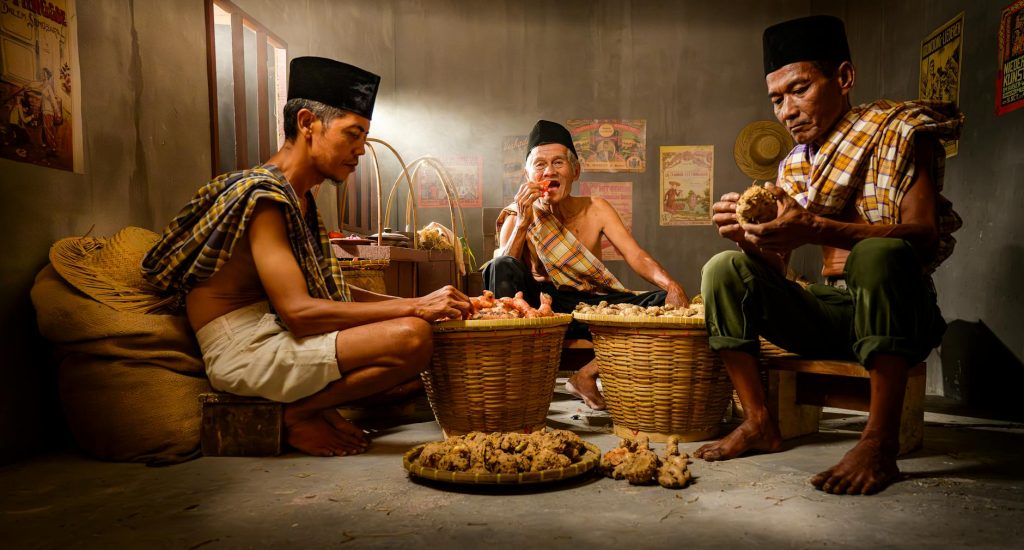 Portrait of Indonesian farmers sorting ginger indoors with baskets.