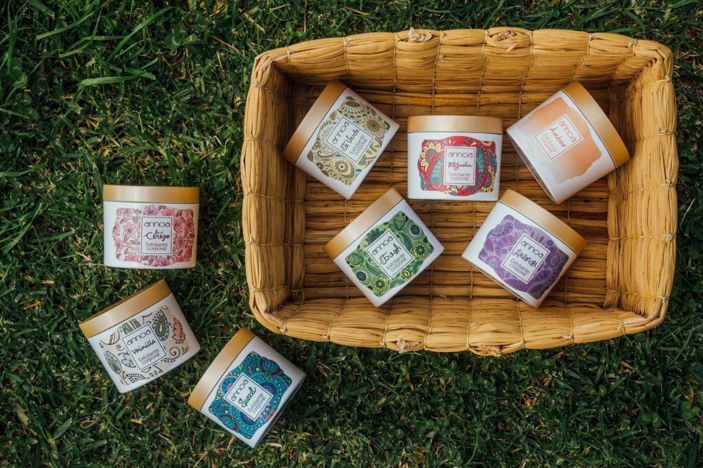 Seven vibrant herbal containers arranged in a bamboo basket on green grass, showcasing unique designs and natural themes.