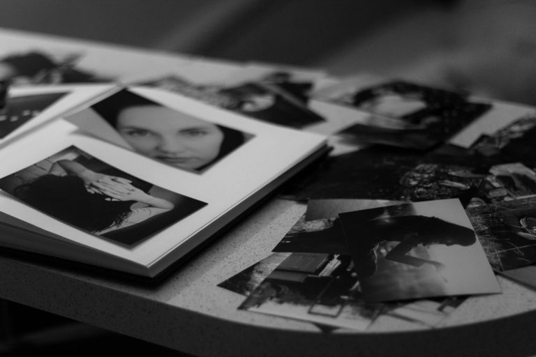 A collection of black and white photos scattered on a table, featuring portraits and artistic compositions.