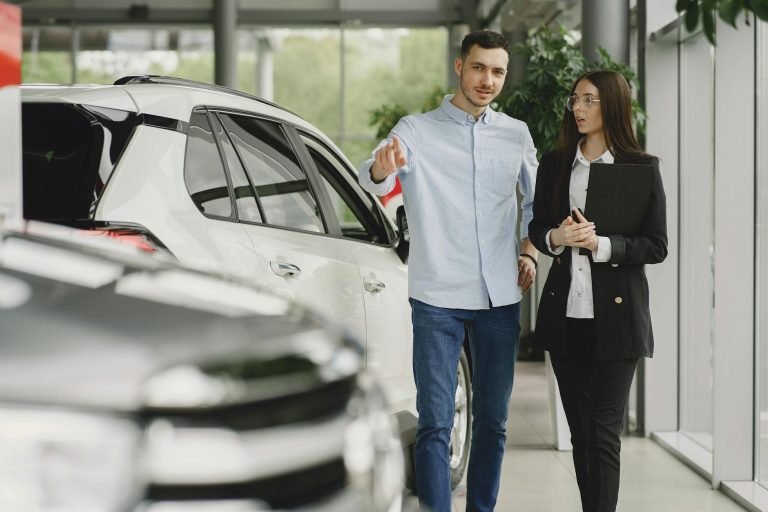 Customer and salesperson discussing a vehicle inside a modern car dealership showroom.