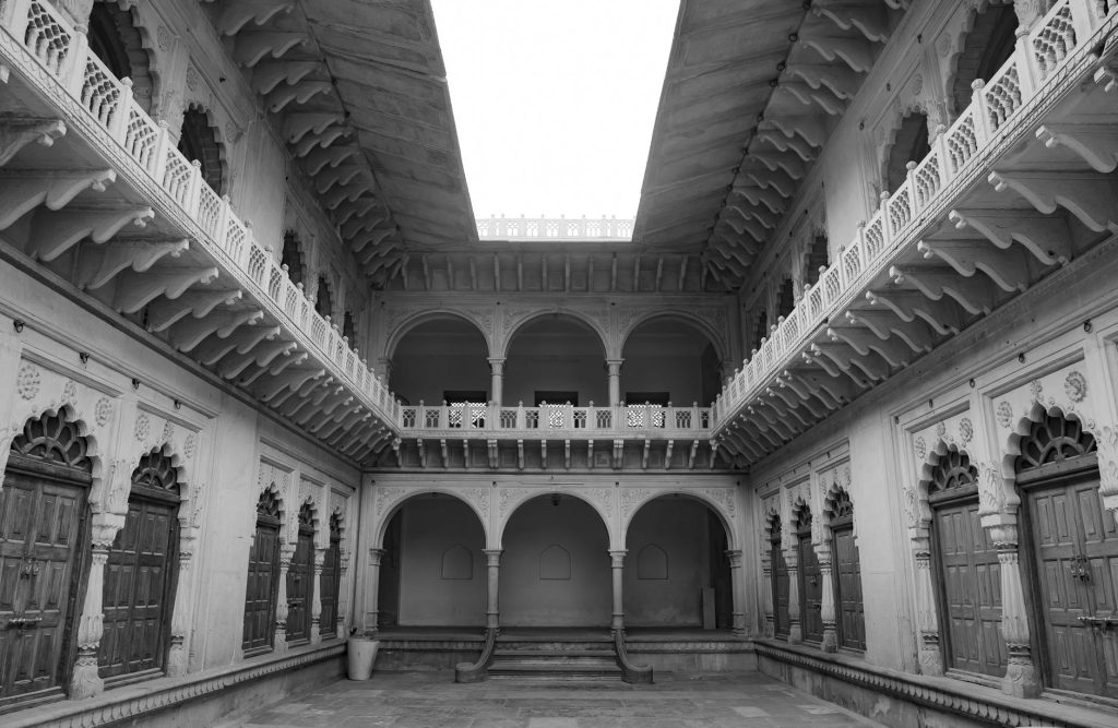 Black and white image of a historical courtyard in India, showcasing intricate architecture.