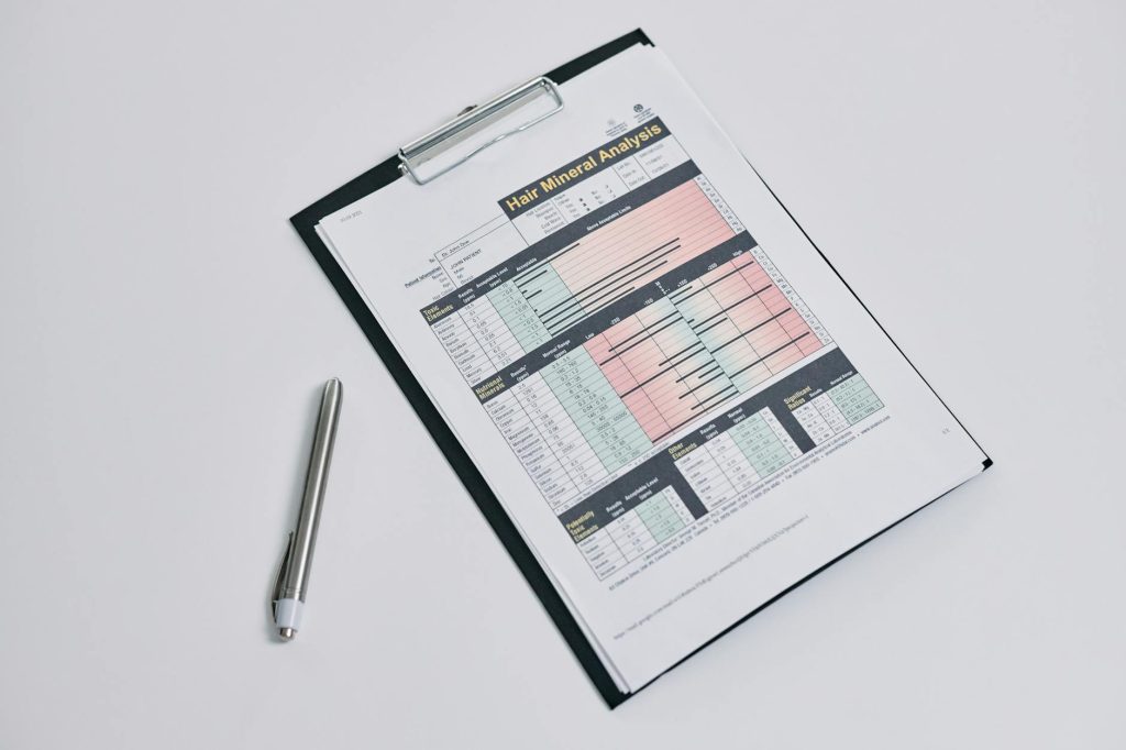 A hair mineral analysis form on a clipboard with a silver pen on a white background.