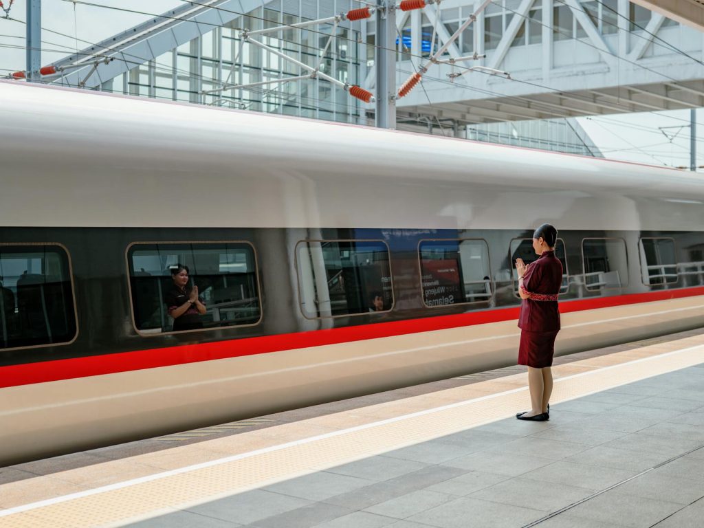 A sleek bullet train at a Jakarta station with a conductor in uniform. Modern transportation captured.