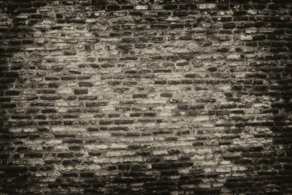 Grayscale textured brick wall background with rough surface.