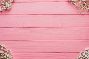 Aesthetic pink wooden background with white baby's breath flowers, ideal for weddings and events.