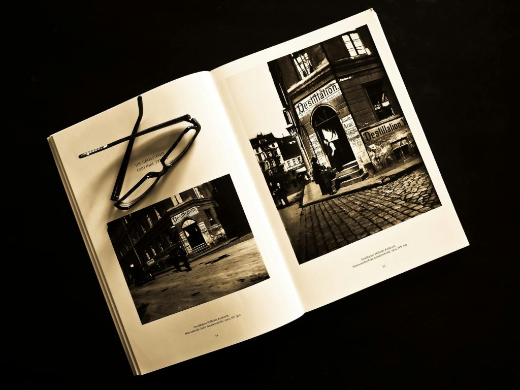 Vintage-style photo book open with eyeglasses resting on pages, showing black and white photography.