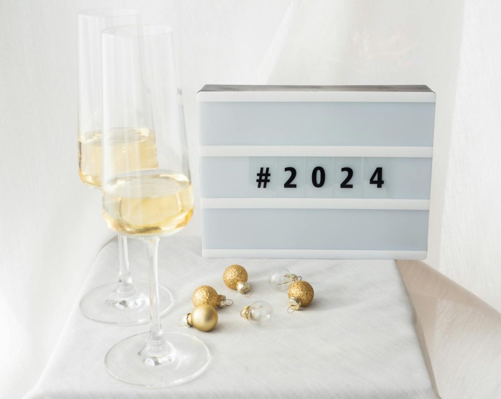 Elegant New Year's Eve setup with champagne glasses, golden Christmas balls, and a 2024 sign.