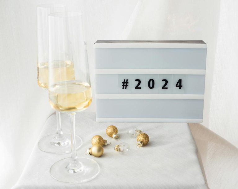 Elegant New Year's Eve setup with champagne glasses, golden Christmas balls, and a 2024 sign.