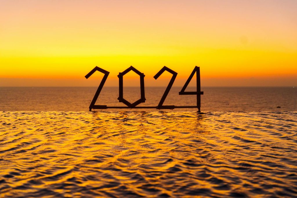 Silhouette of "2024" at sunset reflecting over water, evoking hope and new beginnings.
