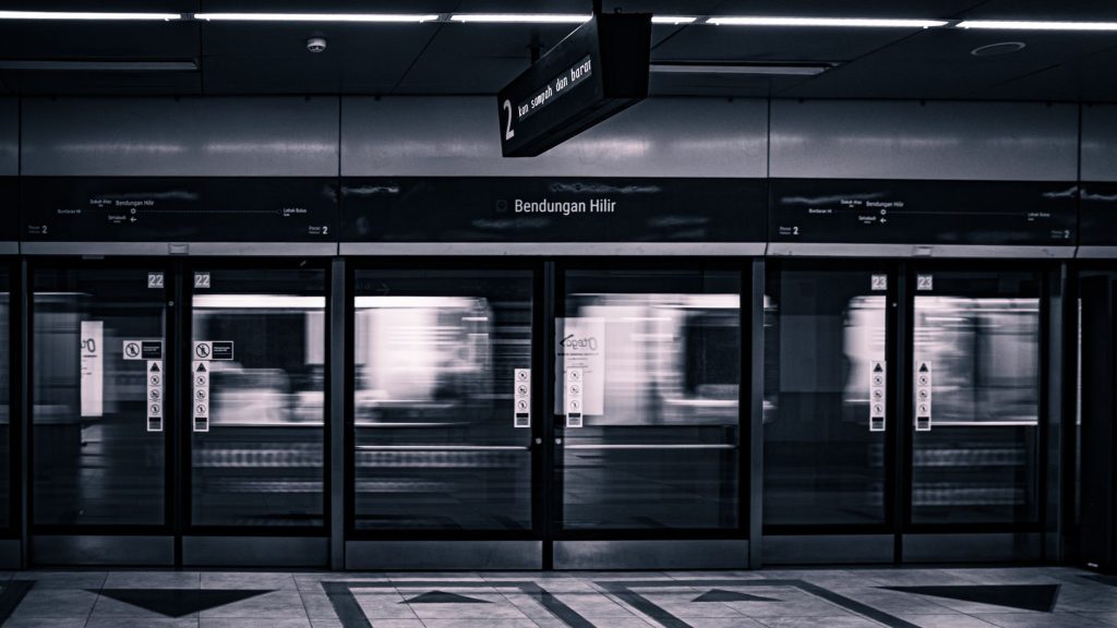 Monochrome image capturing a metro train in motion at Bendungan Hilir station, Jakarta.